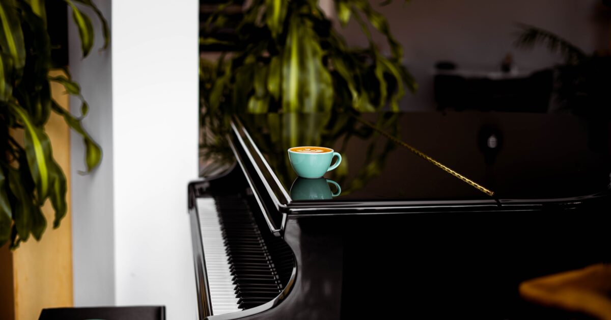 A piano with a cup of coffee laid atop