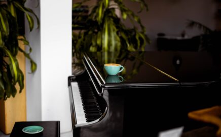 A piano with a cup of coffee laid atop