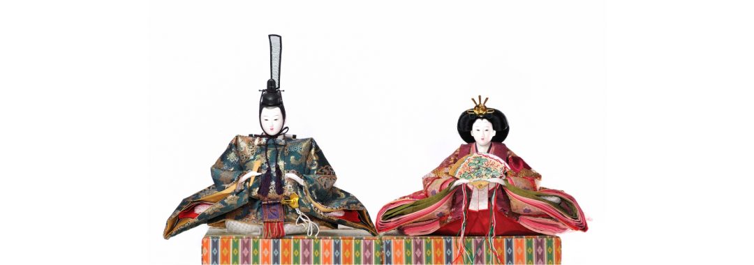 Two Japanese hina dolls against a white background.