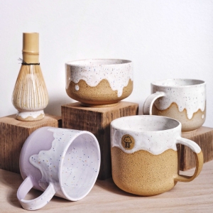 Handmade mugs and tea blows and a matcha whisk on a pottery stand