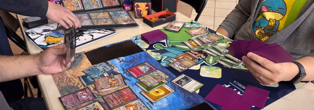 Two people playing the Pokémon Trading Card Game at a table, with cards arranged on colorful playmats.