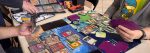 Two people playing the Pokémon Trading Card Game at a table, with cards arranged on colorful playmats.