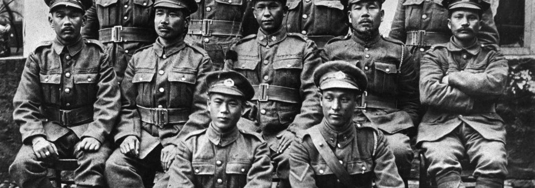 A historic black-and-white group portrait of eleven Japanese-Canadian soldiers posing in military uniforms during the First World War.