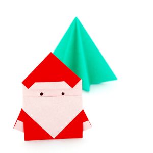 A red and white origami santa and a simple green tree origami on white background.