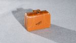 Tiny brown leather suitcase with Winnipeg, Canada in black letters photographed ethafoam with a long shadow.