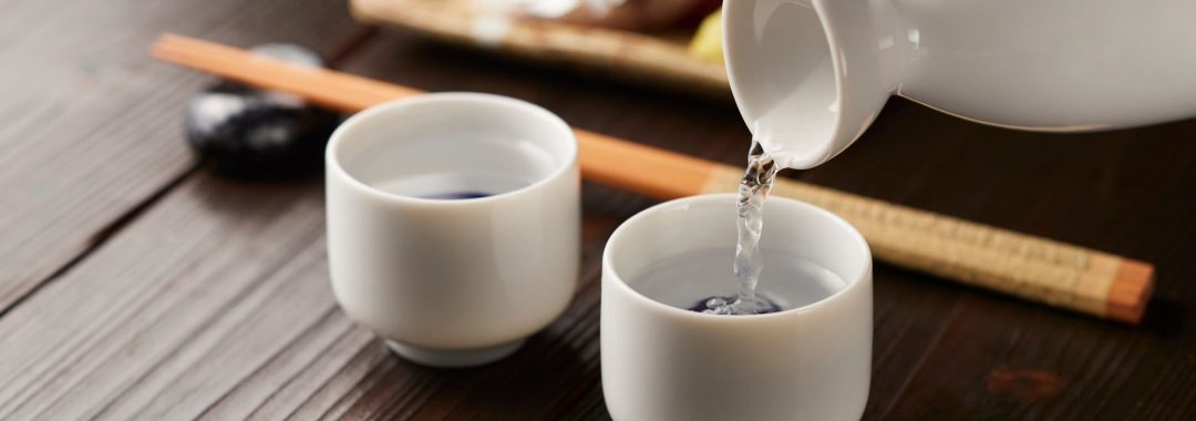 Pouring sake into two while porcelain cups.