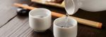 Pouring sake into two while porcelain cups.