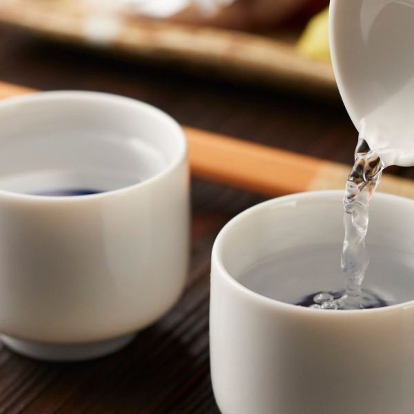 Pouring sake into two while porcelain cups.