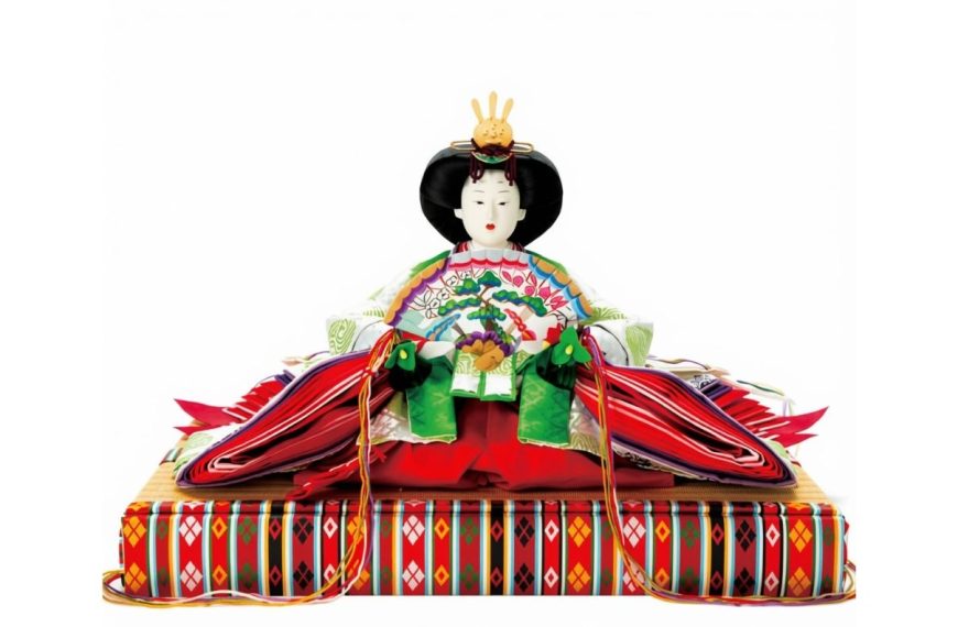 Traditional Japanese Hina doll in an elaborate multi-layered kimono and golden crown, holding a decorative fan while seated.