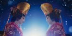 Two performers in ornate red kimonos and tall golden headpieces facing each other against a blue starry background.