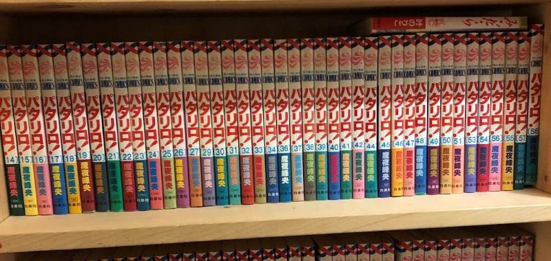Three layers of bookshelves packed with Japanese manga books.