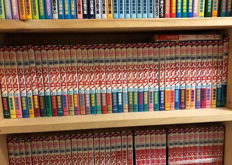 Three layers of bookshelves packed with Japanese manga books.